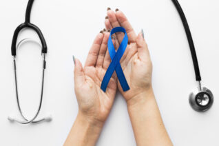 crop hands with blue ribbon near stethoscope scaled e1754387486515
